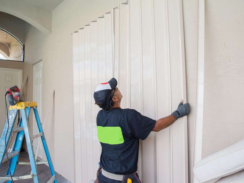Crew installing accordion hurricane shutters on a Fort Myers home